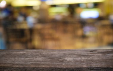 Restoranın soyut bulanık arka planının önündeki boş, siyah ahşap masa. Ürünlerinizi görüntülemek ya da montajlamak için kullanılabilir.