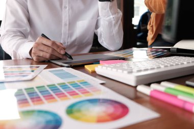 Grafik tasarımcısı dijital tablet üzerinde çalışıyor. Grafik tablet ve renk örneklerine resim çizen sanatçı