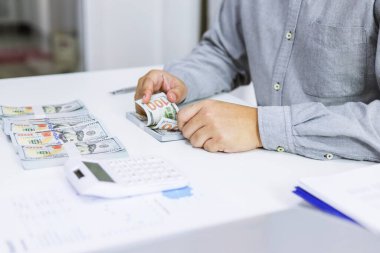 Yatırım çizelgelerini analiz eden ve belgelerin üzerindeki hesap makinesi tuşlarına basan bir işadamı. Muhasebe Kavramı