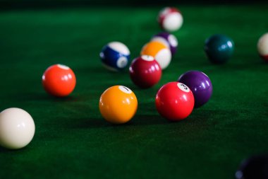 Adamın eli ve Cue kolu bilardo oynuyor ya da yeşil bir bilardo masasında bilardo topu fırlatmaya hazırlanıyor. Yeşil frizde renkli bilardo topları