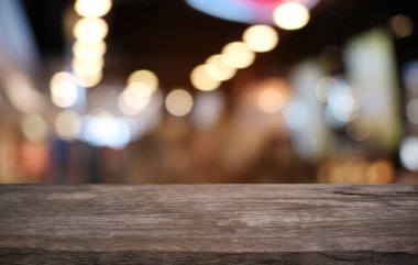 Restoranın soyut bulanık arka planının önündeki boş, siyah ahşap masa. Ürünlerinizi görüntülemek ya da montajlamak için kullanılabilir. 