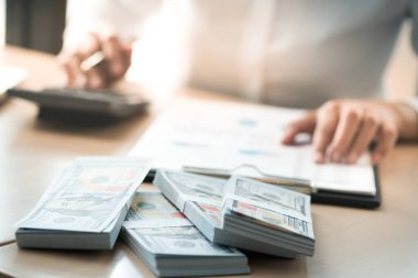 Yatırım çizelgelerini analiz eden ve belgelerin üzerinde hesap makinesi tuşlarına basan bir iş kadını. Muhasebe Kavramı