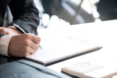 Yatırım çizelgelerini analiz eden ve belgelerin üzerindeki hesap makinesi tuşlarına basan bir işadamı. Muhasebe Kavramı