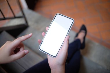 Asyalı kızlar ellerinde alışveriş torbaları tutuyor. Alışveriş merkezinin ellerinde cep telefonunun boş fotokopi ekranını tutan tüketim yaşam tarzı kavramı