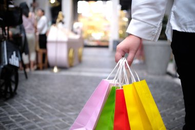 Asyalı kızlar ellerinde alışveriş torbaları tutuyor. Alışveriş merkezinde tüketim yaşam tarzı kavramı