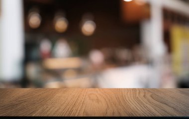 Restoranın soyut bulanık arka planının önündeki boş, siyah ahşap masa. Ürünlerinizi görüntülemek ya da montajlamak için kullanılabilir. 