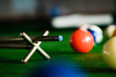 Adamın eli ve Cue kolu bilardo oynuyor ya da yeşil bir bilardo masasında bilardo topu fırlatmaya hazırlanıyor. Yeşil frizde renkli bilardo topları