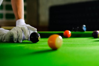 Adamın eli ve Cue kolu bilardo oynuyor ya da yeşil bir bilardo masasında bilardo topu fırlatmaya hazırlanıyor. Yeşil frizde renkli bilardo topları
