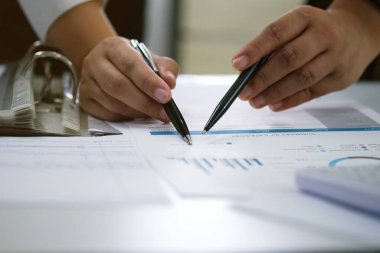 Yatırım çizelgelerini analiz eden ve belgelerin üzerindeki hesap makinesi tuşlarına basan bir işadamı. Muhasebe Kavramı