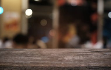 Restoranın soyut bulanık arka planının önündeki boş, siyah ahşap masa. Ürünlerinizi görüntülemek ya da montajlamak için kullanılabilir. 