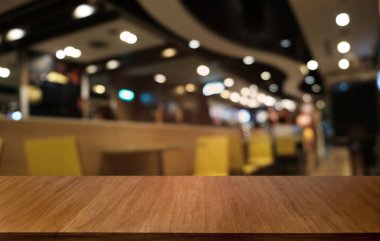 Restoranın soyut bulanık arka planının önündeki boş, siyah ahşap masa. Ürünlerinizi görüntülemek ya da montajlamak için kullanılabilir. 