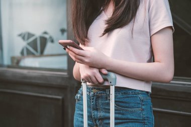 Gezgin kadının elleri telefon haritasına bakarak akıllı telefon kullanıyor.