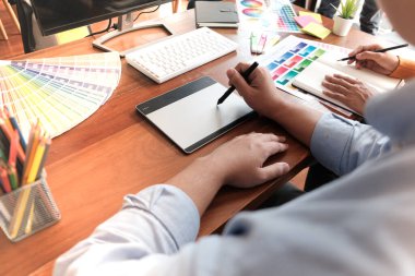 Grafik tasarımcısı dijital tablet üzerinde çalışıyor. Grafik tablet ve renk örneklerine resim çizen sanatçı