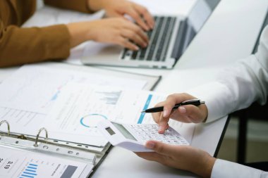 Yatırım çizelgelerini analiz eden ve belgelerin üzerindeki hesap makinesi tuşlarına basan bir işadamı. Muhasebe Kavramı