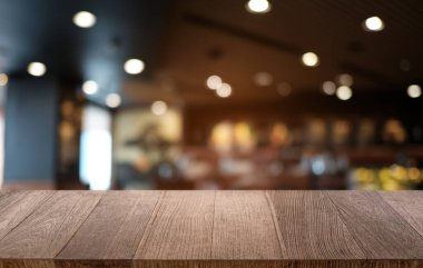Restoranın soyut bulanık arka planının önündeki boş, siyah ahşap masa. Ürünlerinizi görüntülemek ya da montajlamak için kullanılabilir. 