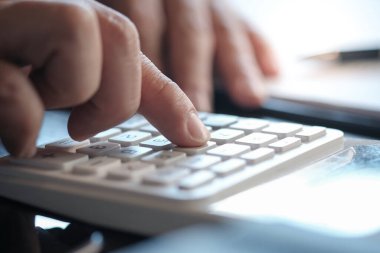 Yatırım çizelgelerini analiz eden ve belgelerin üzerindeki hesap makinesi tuşlarına basan bir işadamı. Muhasebe Kavramı