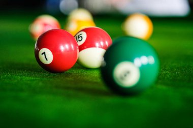 Adamın eli ve Cue kolu bilardo oynuyor ya da yeşil bir bilardo masasında bilardo topu fırlatmaya hazırlanıyor. Yeşil frizde renkli bilardo topları