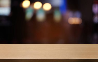 Restoranın soyut bulanık arka planının önündeki boş, siyah ahşap masa. Ürünlerinizi görüntülemek ya da montajlamak için kullanılabilir. 