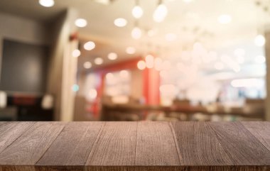 Restoranın soyut bulanık arka planının önündeki boş, siyah ahşap masa. Ürünlerinizi görüntülemek ya da montajlamak için kullanılabilir.