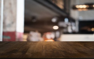 Restoranın soyut bulanık arka planının önündeki boş, siyah ahşap masa. Ürünlerinizi görüntülemek ya da montajlamak için kullanılabilir. 