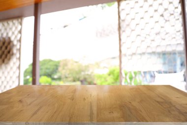 Kafenin soyut bulanık arka planının önündeki boş ahşap masa. Ürünlerinizi görüntülemek veya montajlamak için kullanılabilir. Ürünün görüntülenmesi için modelleyin