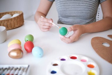 Paskalya yumurtalarını evde boyayan kadın. Aile Paskalya için hazırlanıyor. Paskalya yumurtası taşıyan bir kızın elleri.. 