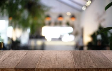 Restoranın soyut bulanık arka planının önündeki boş, siyah ahşap masa. Ürünlerinizi görüntülemek ya da montajlamak için kullanılabilir.