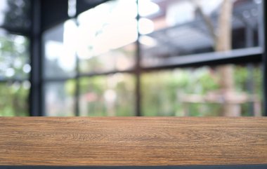 Restoranın soyut bulanık arka planının önündeki boş, siyah ahşap masa. Ürünlerinizi görüntülemek ya da montajlamak için kullanılabilir.