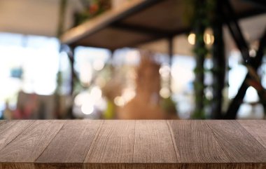 Restoranın soyut bulanık arka planının önündeki boş, siyah ahşap masa. Ürünlerinizi görüntülemek ya da montajlamak için kullanılabilir.