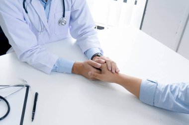 Doktorun hastasının elini tutması ve erkek hastasına el konseptine yardım etmesi.