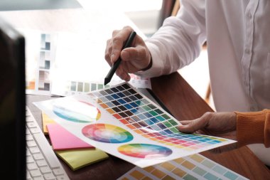 Grafik tasarımcısı dijital tablet üzerinde çalışıyor. Grafik tablet ve renk örneklerine resim çizen sanatçı