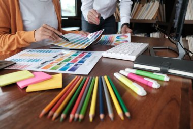 Grafik tasarımcısı dijital tablet üzerinde çalışıyor. Grafik tablet ve renk örneklerine resim çizen sanatçı