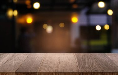 Restoranın soyut bulanık arka planının önündeki boş, siyah ahşap masa. Ürünlerinizi görüntülemek ya da montajlamak için kullanılabilir.