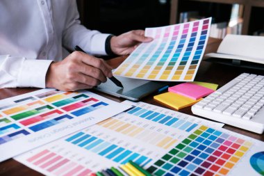 Grafik tasarımcısı dijital tablet üzerinde çalışıyor. Grafik tablet ve renk örneklerine resim çizen sanatçı