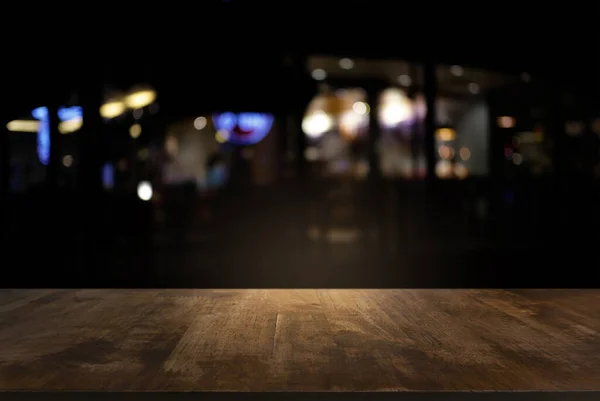 Bokeh ışığının soyut bulanık arka planının önündeki karanlık ahşap masa boş. Ürünlerinizi görüntülemek veya montajlamak için kullanılabilir. Ürünün görüntülenmesi için modelleyin.