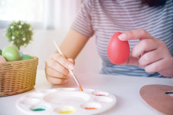 Woman painting Easter eggs at home. family preparing for Easter. Hands of a girl with a easter egg.