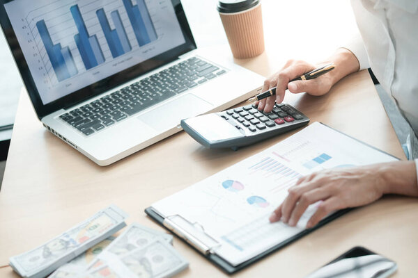 Businesswoman analyzing investment charts and pressing calculator buttons over documents. Accounting Concept