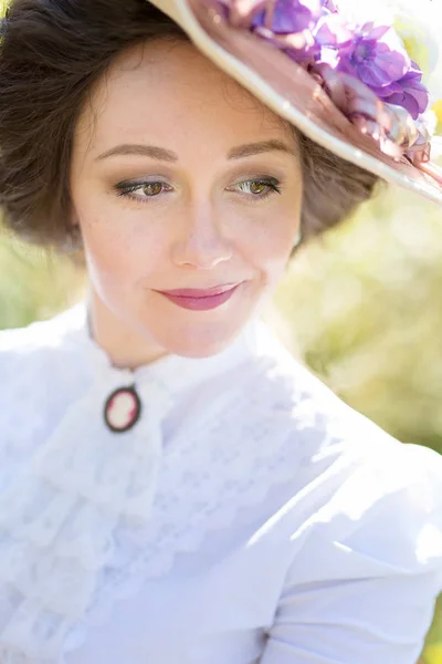 美丽的女士在帽子与花在一个历史性的礼服微笑 — 图库照片