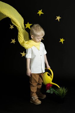 gece gökyüzünde yıldızlar sarı bir sulama olabilir üzerinden kırmızı bir gül sulama ile karşı sarı fularlı küçük bir çocuk