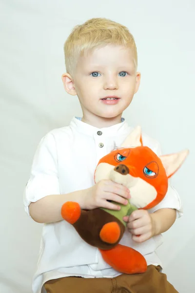 little smiling boy with toy Fox in hand on white background