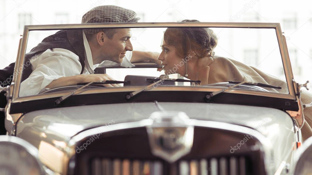 Two in a convertible talking, a lady and a man in the style of the 30s of the last century, historical photography