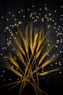 Yatay bileşim hala siyah yanmış tahtaların ve pasta yıldızlarının arka planında buğday kulaklarıyla yaşam