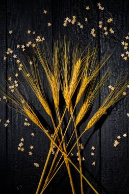 Yatay bileşim hala siyah yanmış tahtaların ve pasta yıldızlarının arka planında buğday kulaklarıyla yaşam