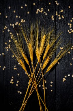 Yatay bileşim hala siyah yanmış tahtaların ve pasta yıldızlarının arka planında buğday kulaklarıyla yaşam