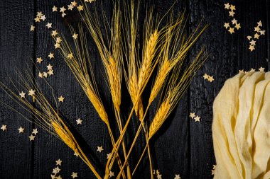 Yatay bileşim hala siyah yanmış tahtaların ve pasta yıldızlarının arka planında buğday kulaklarıyla yaşam