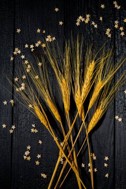 Yatay bileşim hala siyah yanmış tahtaların ve pasta yıldızlarının arka planında buğday kulaklarıyla yaşam