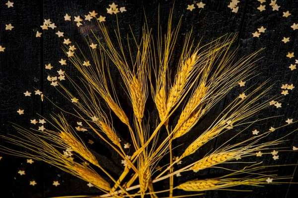 horizontal composition still Life with wheat ears on the background of black burnt boards and pastry stars