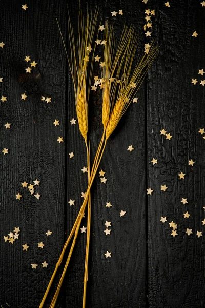 horizontal composition still Life with wheat ears on the background of black burnt boards and pastry stars