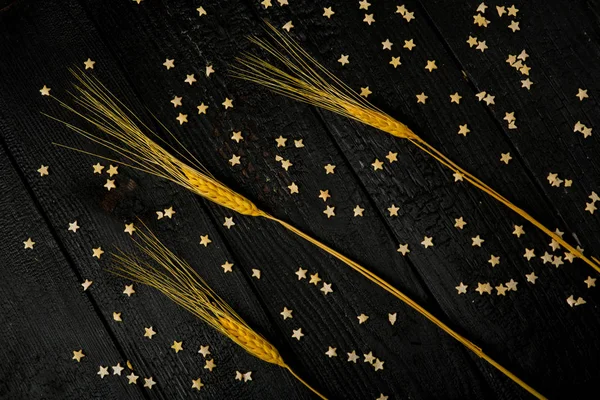 horizontal composition still Life with wheat ears on the background of black burnt boards and pastry stars