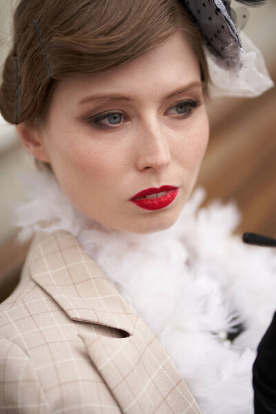 Portrait of a Beautiful brunette in a black retro hat and white jacket, sitting and looking away and Smoking. Historical reconstruction                               